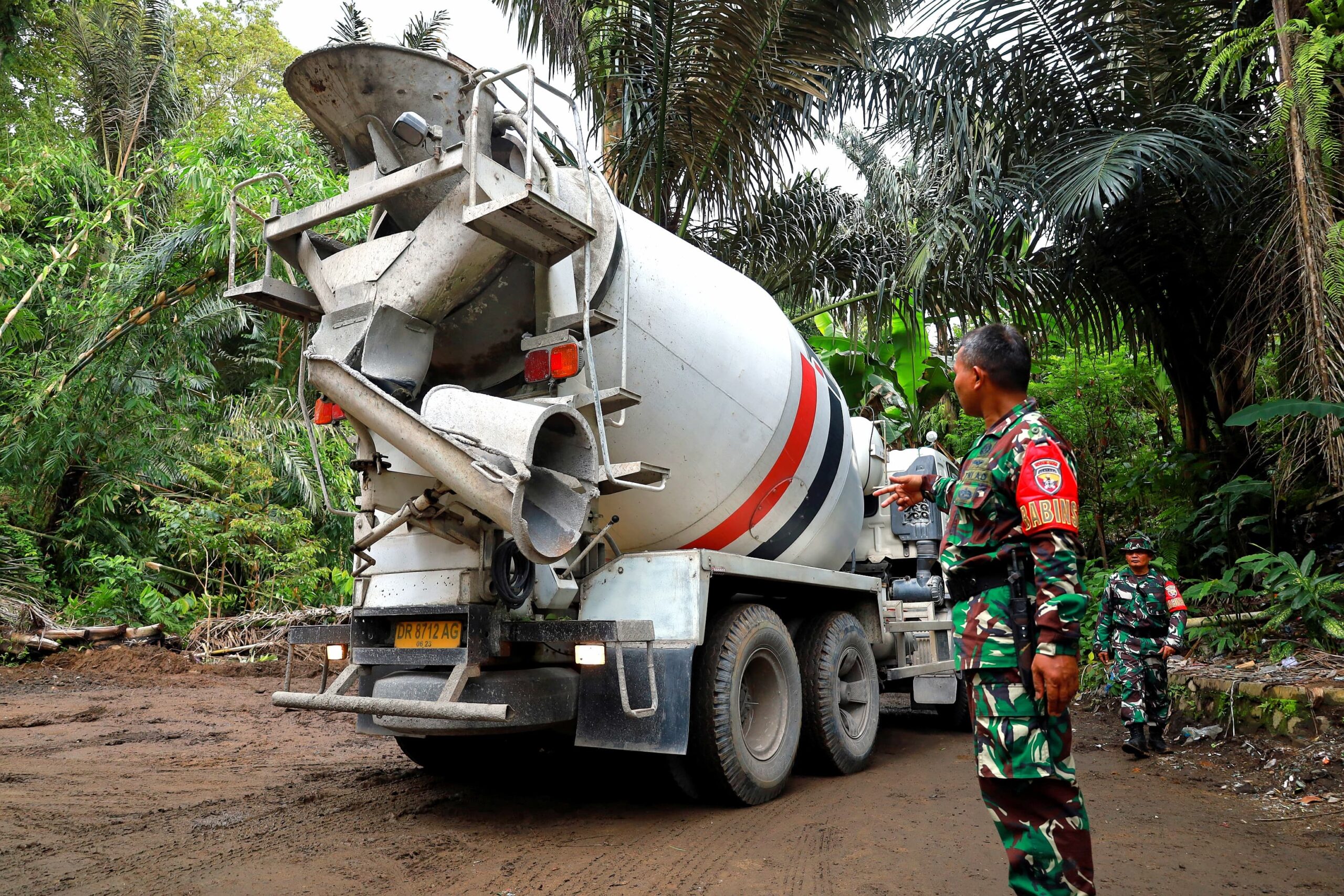 TMMD : Seorang anggota TNI dari Kodim 1606/Mataram mengatur kendaraan “molen” yang membawa bahan untuk rabat jalan di jalan baru Giri Madia – Dasan Griya, Lingsar, Lombok Barat.